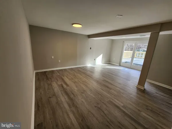 a view of an empty room with wooden floor and closet