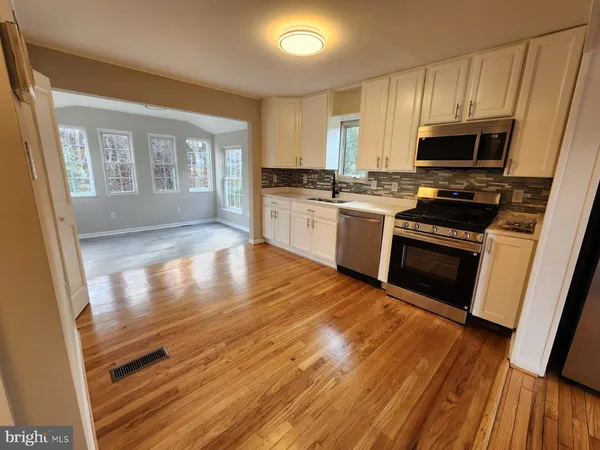 a kitchen with granite countertop wooden floors a stove and white stainless steel appliances