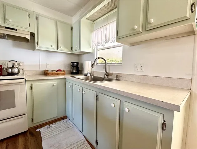 a kitchen with stainless steel appliances granite countertop a sink dishwasher a refrigerator and cabinets with wooden floor