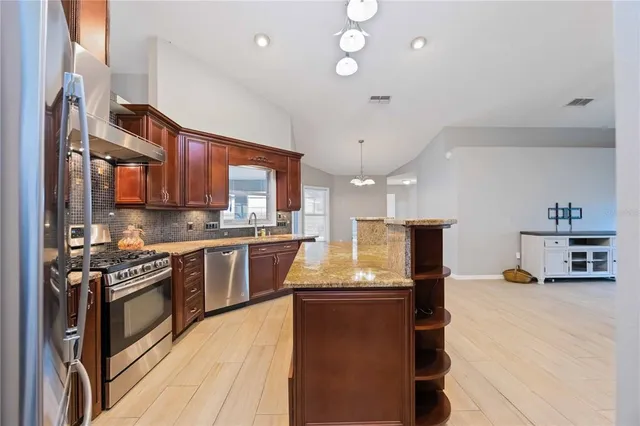 a kitchen with stainless steel appliances granite countertop sink stove and refrigerator