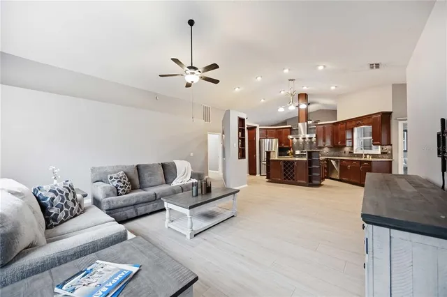 a living room with furniture kitchen view and a chandelier