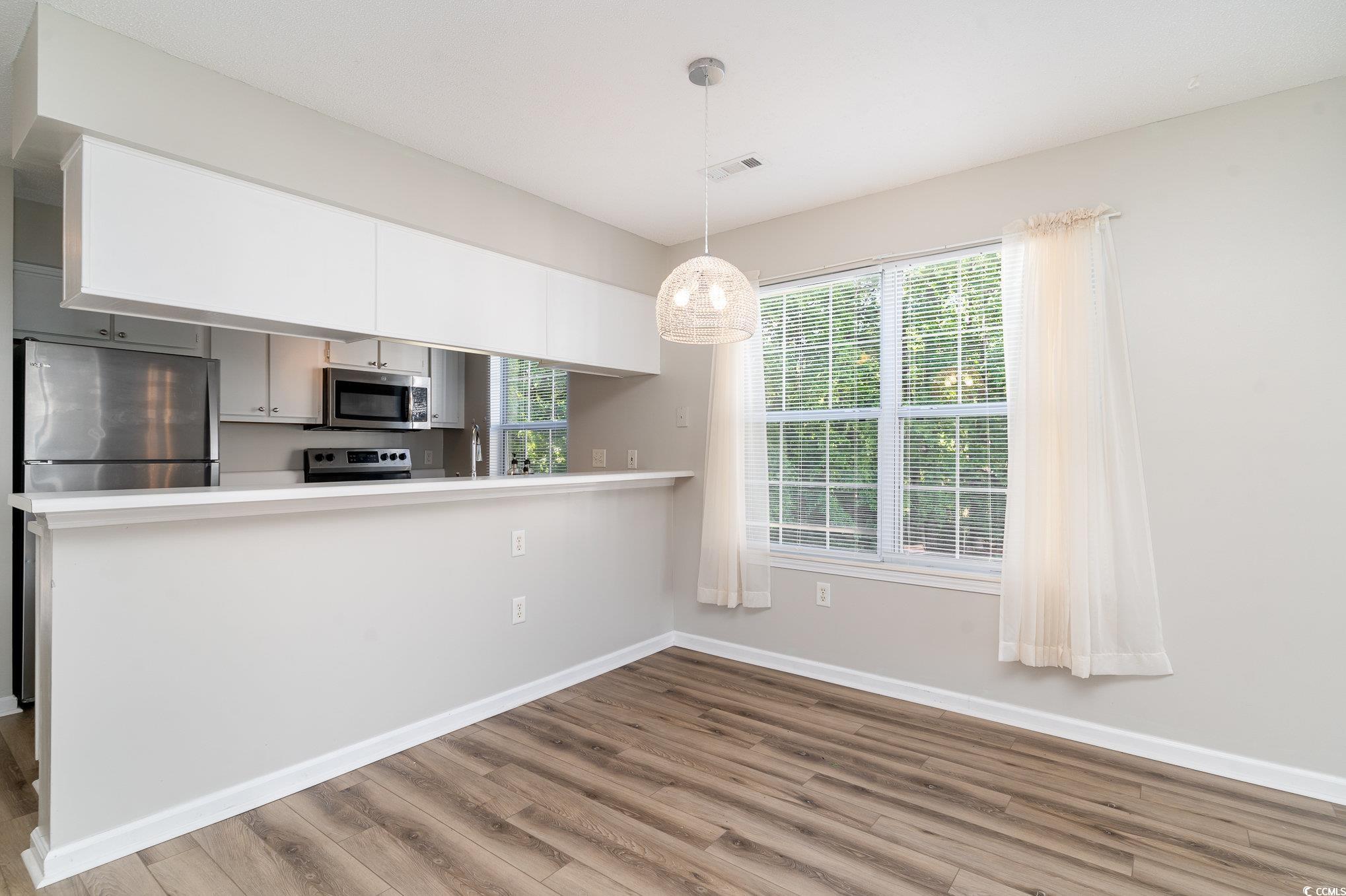 651 Woodmoor Drive, Unit 201 Murrells Inlet, SC 29576 - Photo 11 of 35 Kitchen featuring stainless steel appliances, light countertops, light wood-style floors, pendant lighting, and healthy amount of natural light