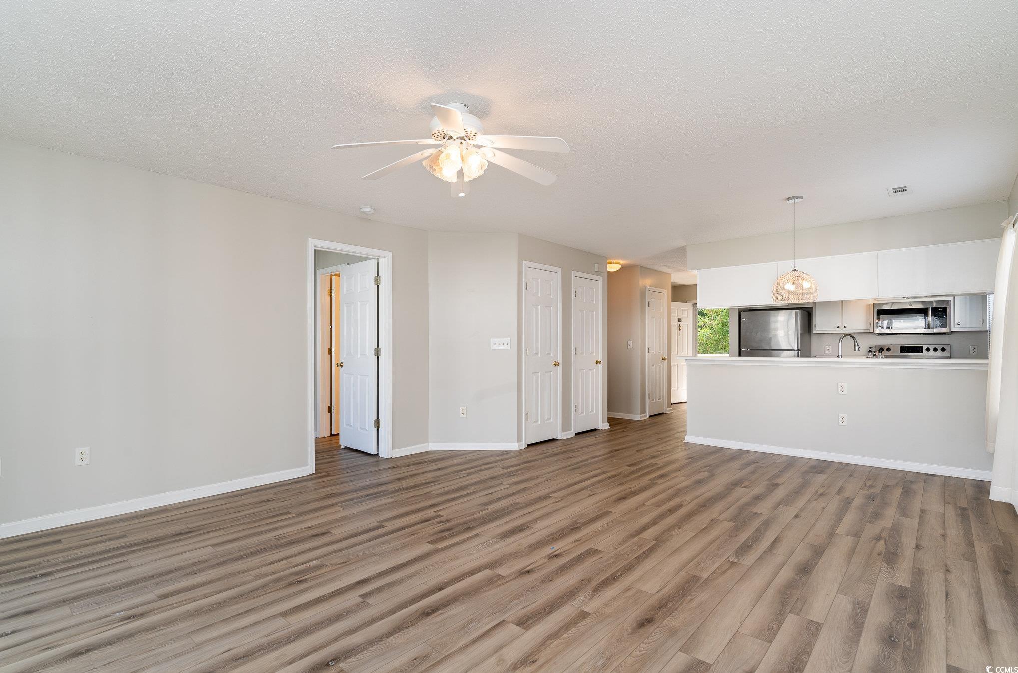 651 Woodmoor Drive, Unit 201 Murrells Inlet, SC 29576 - Photo 5 of 35 Unfurnished living room featuring light wood finished floors, a textured ceiling, and a ceiling fan