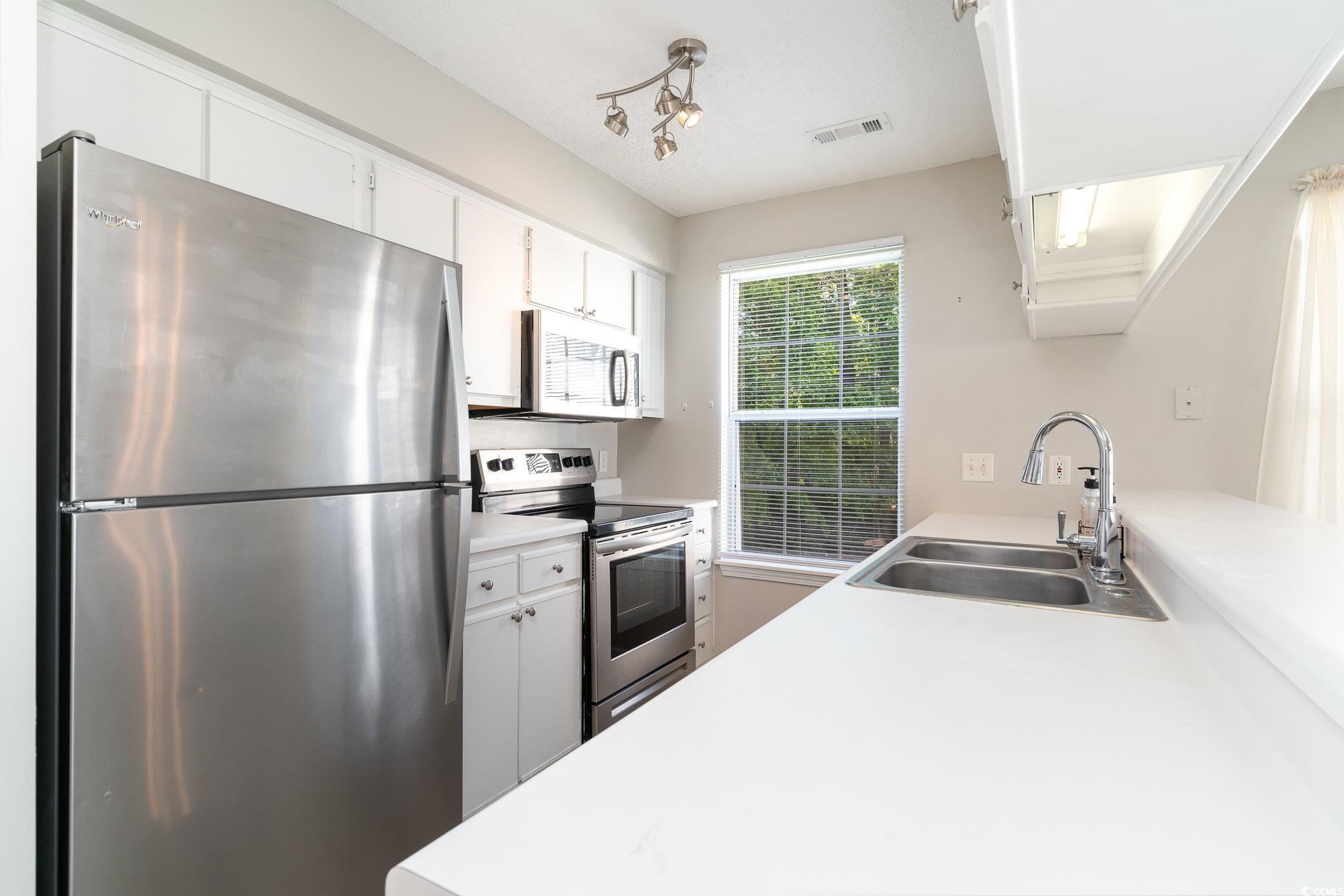651 Woodmoor Drive, Unit 201 Murrells Inlet, SC 29576 - Photo 7 of 35 Kitchen with appliances with stainless steel finishes, light countertops, and white cabinets