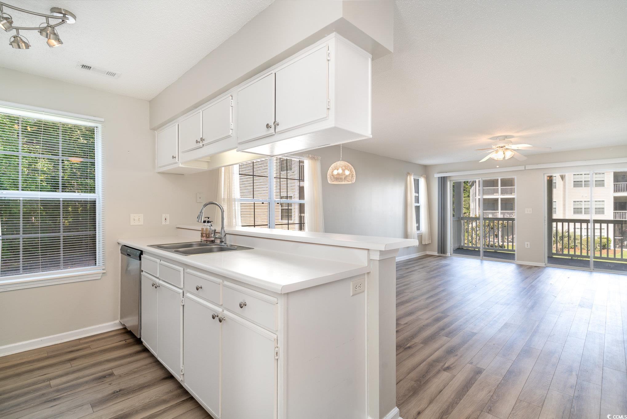 651 Woodmoor Drive, Unit 201 Murrells Inlet, SC 29576 - Photo 8 of 35 Kitchen with white cabinets, light countertops, a peninsula, and light wood-style flooring