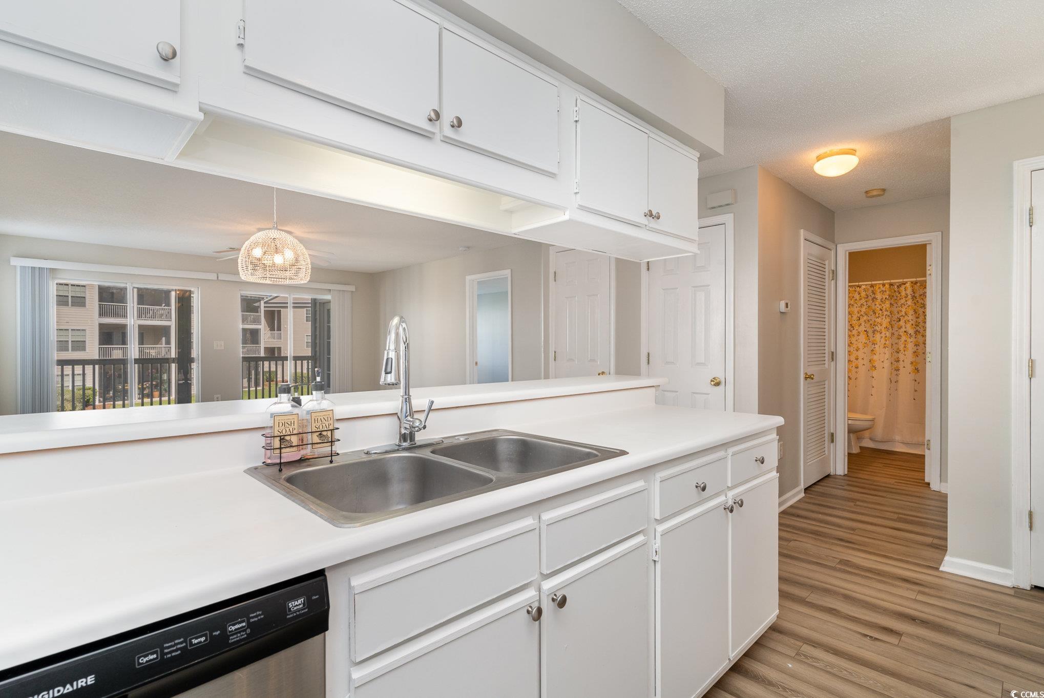 651 Woodmoor Drive, Unit 201 Murrells Inlet, SC 29576 - Photo 10 of 35 Kitchen featuring white cabinetry, dishwasher, light countertops, light wood-style flooring, and a textured ceiling
