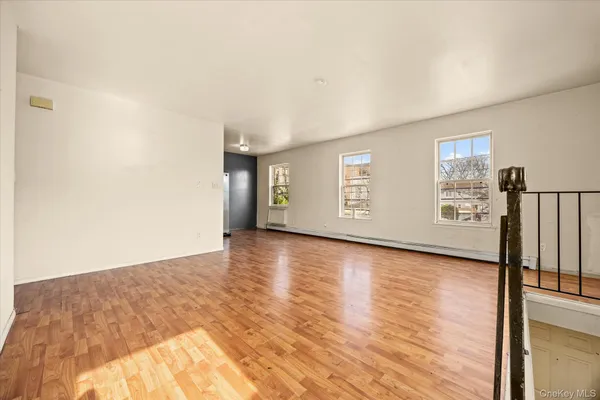 a view of an empty room with window and wooden floor