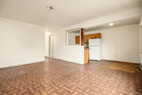 a view of a big room with wooden floor and a refrigerator