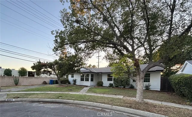 a view of a white house in a big yard with large trees