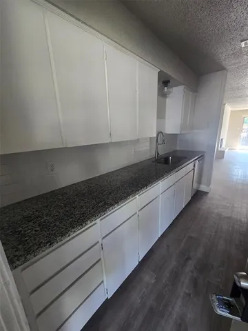 a kitchen with granite countertop white cabinets and sink