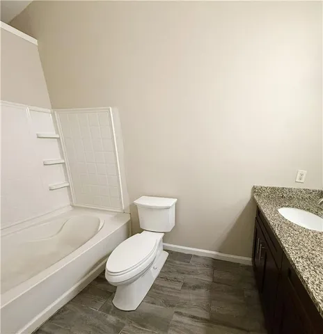 a bathroom with a granite countertop toilet and a bathtub