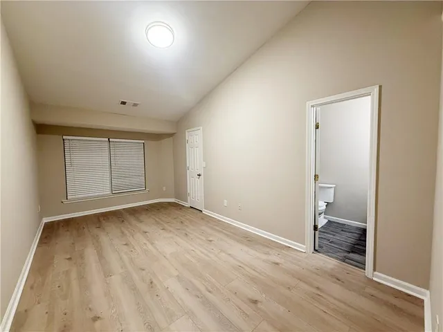 an empty room with wooden floor and bathroom