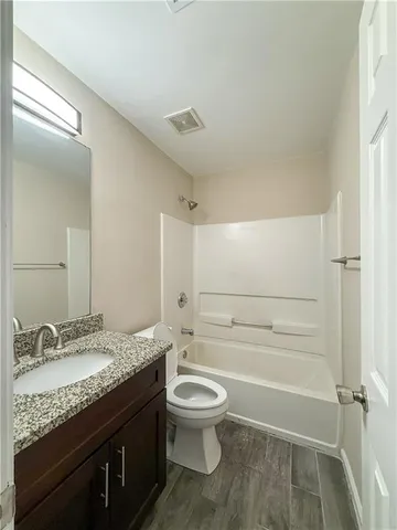 a bathroom with a granite countertop toilet a sink and a mirror