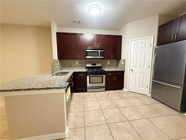 a kitchen with stainless steel appliances granite countertop a refrigerator and a stove top oven
