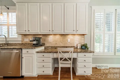 a kitchen with granite countertop white cabinets and window
