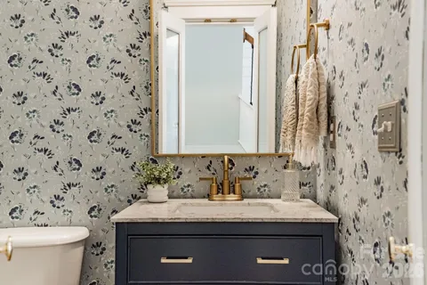 a bathroom with a granite countertop sink a toilet and a mirror