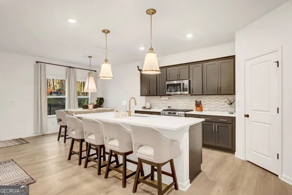a kitchen with kitchen island granite countertop a sink a center island and appliances