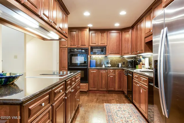 a kitchen with stainless steel appliances granite countertop a sink a stove and a refrigerator