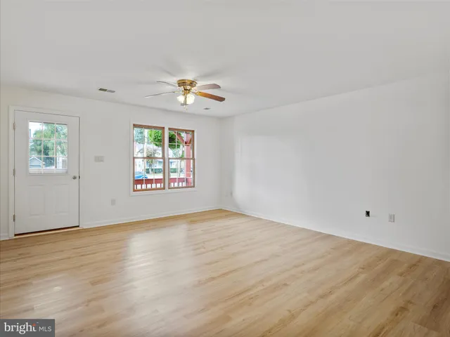 an empty room with windows and chandelier fan