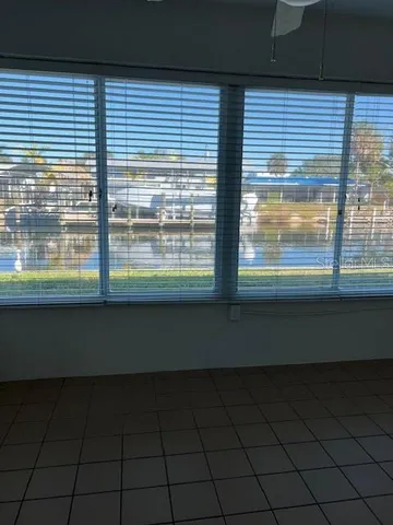 a view of empty room with wooden floor and a window