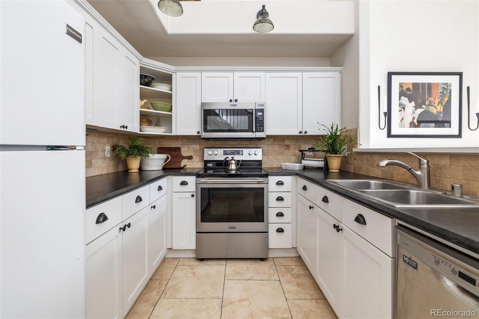 4035 South Dillon Way, Unit 204 Aurora, CO 80014 - Photo 9 of 24 a kitchen with granite countertop a stove top oven sink and cabinets