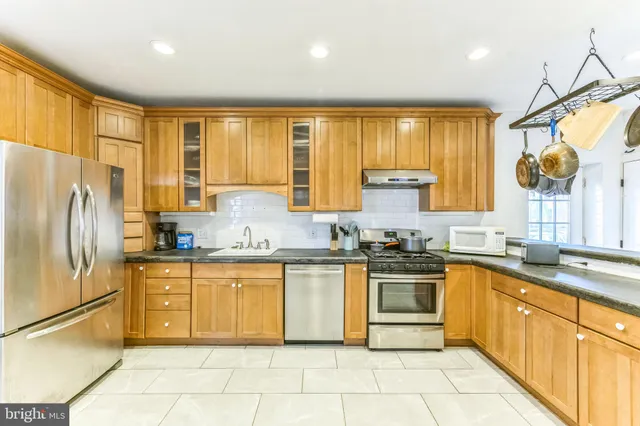 a kitchen with stainless steel appliances granite countertop a stove a sink and a refrigerator
