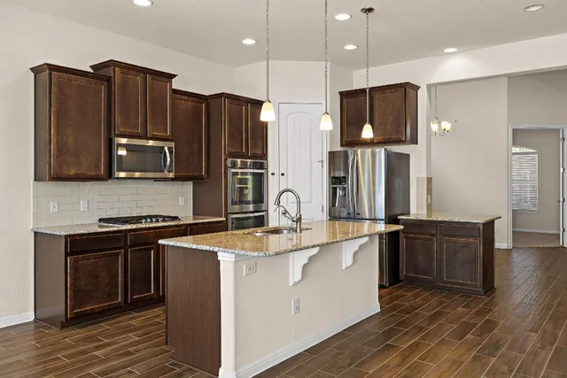 a kitchen with stainless steel appliances granite countertop a refrigerator stove and wooden cabinets