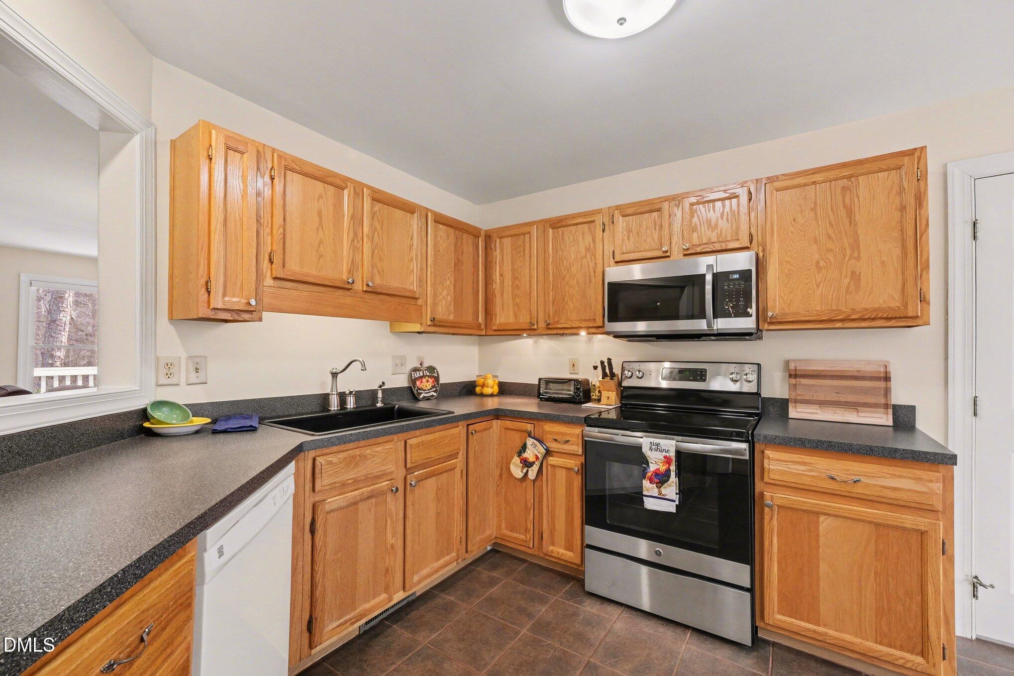 2404 Bane Road Efland, NC 27243 - Photo 15 of 46 a kitchen with stainless steel appliances granite countertop a sink stove and microwave