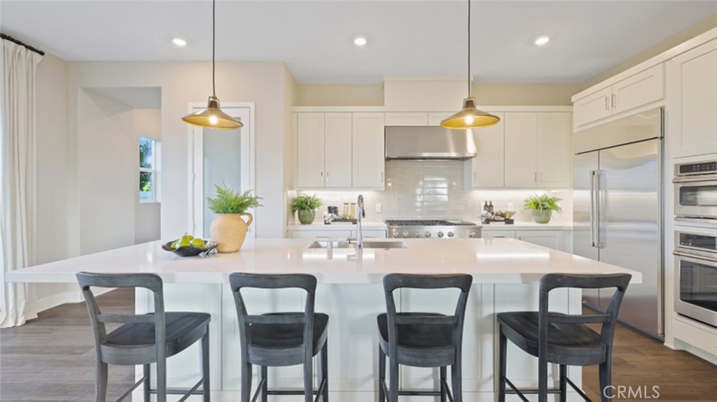 a kitchen with stainless steel appliances granite countertop a table chairs and a refrigerator