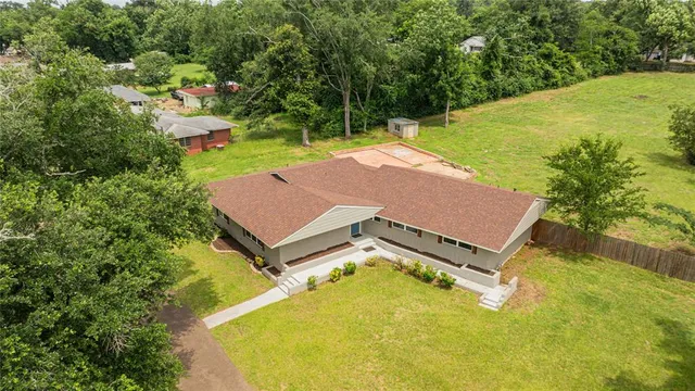 an aerial view of a house with swimming pool and large trees