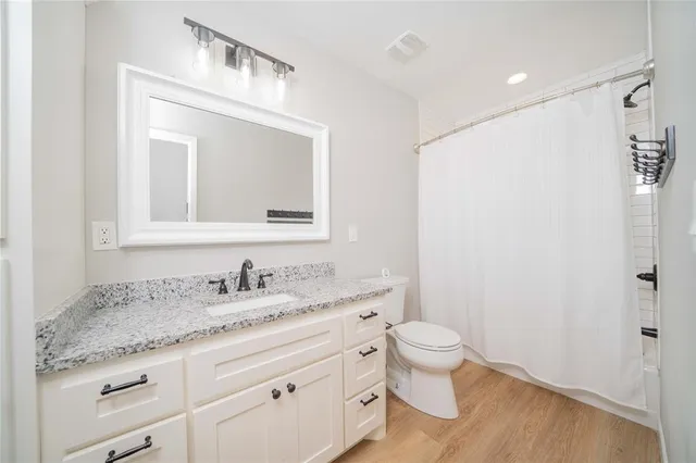 a bathroom with a granite countertop sink a toilet and a mirror