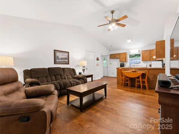 a living room with furniture kitchen view and a chandelier