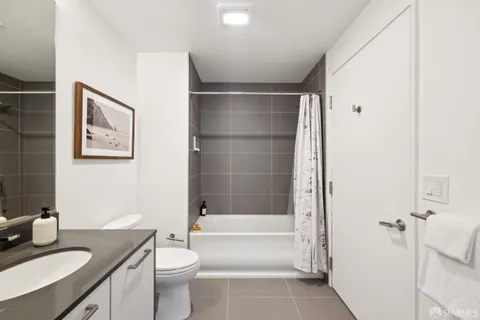 a bathroom with a granite countertop bathtub sink vanity mirror and toilet