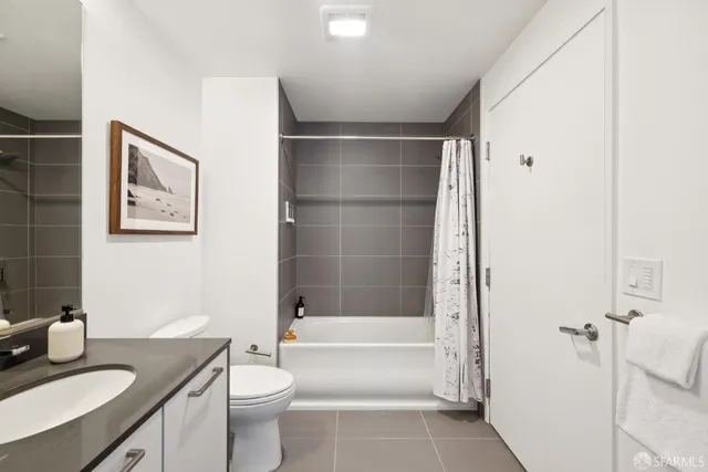 a bathroom with a granite countertop bathtub sink vanity mirror and toilet
