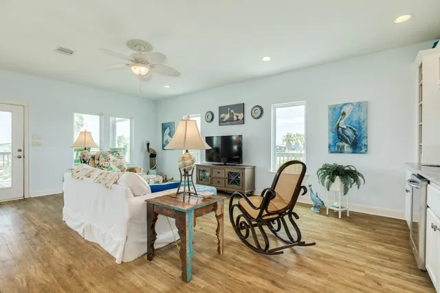 a living room with furniture a flat screen tv and a wooden floor