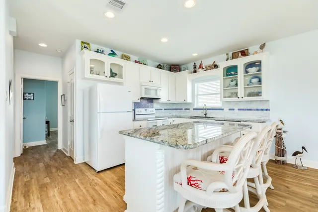 a dining hall with stainless steel appliances granite countertop a stove a sink a dining table and chairs with wooden floor