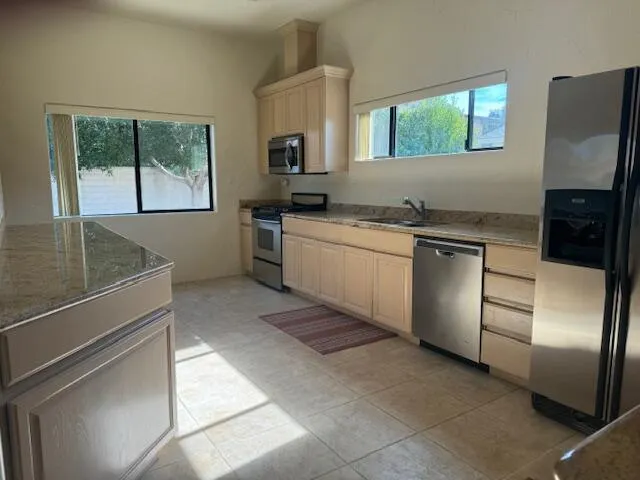 a kitchen with stainless steel appliances granite countertop a refrigerator sink and stove