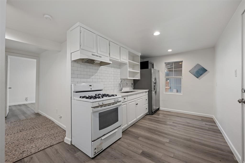 901 Valdez Street, Unit A Austin, TX 78741 - Photo 2 of 16 Kitchen featuring white gas range oven, ventilation hood, recessed lighting, wood-look vinyl flooring, and light countertops