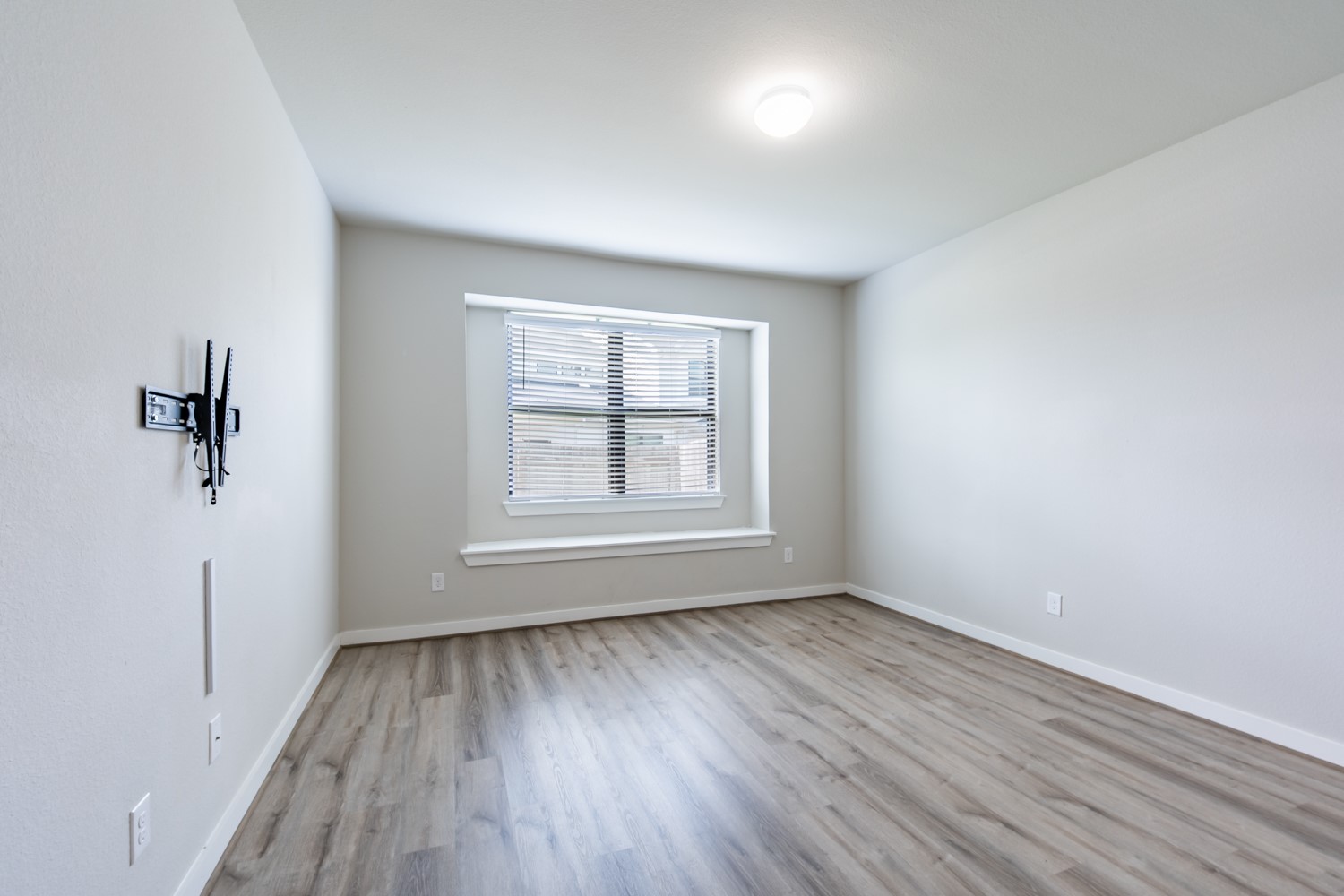 147 Waterside Road, Unit A Buda, TX 78610 - Photo 14 of 27 A well-lit, neutral-toned room features durable hardwood-style flooring and an integrated window for natural illumination.