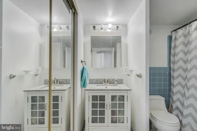 a bathroom with a double vanity sink mirror and toilet