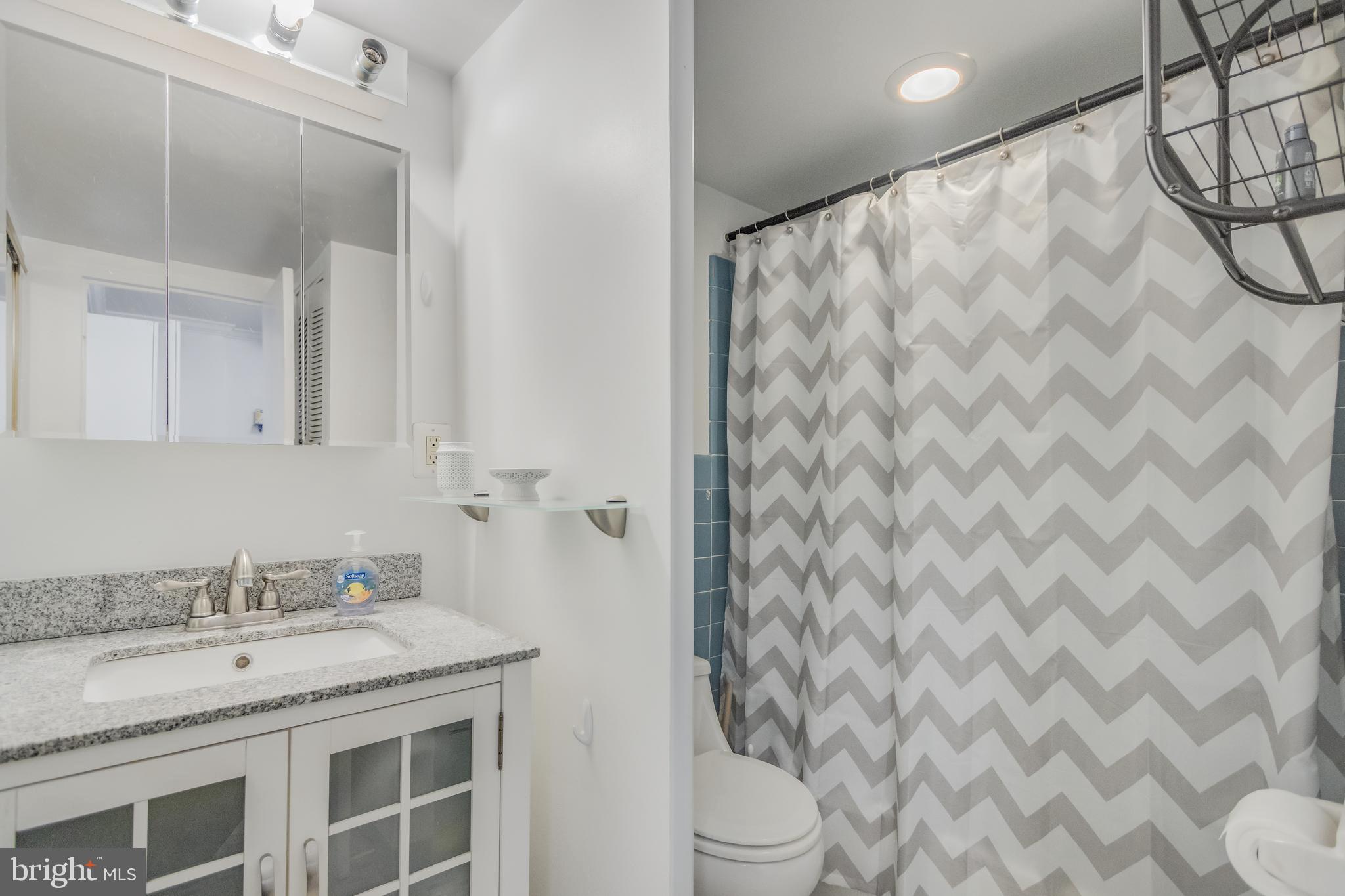 922 24th Street Northwest, Unit 415 Washington, DC 20037 - Photo 7 of 25 a bathroom with a granite countertop sink and a mirror