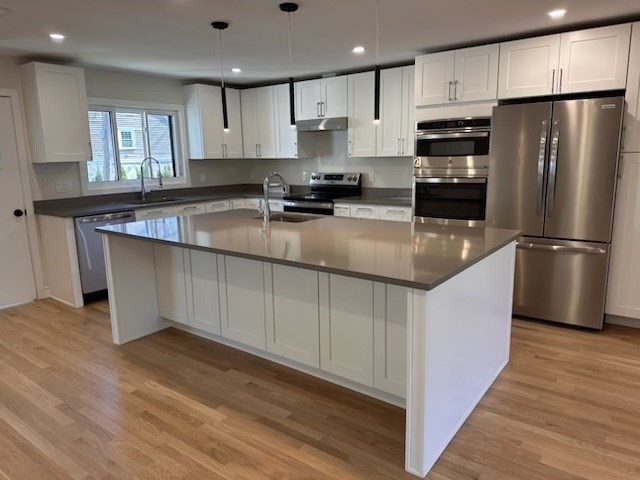 a kitchen with stainless steel appliances granite countertop a refrigerator a stove a sink and a microwave