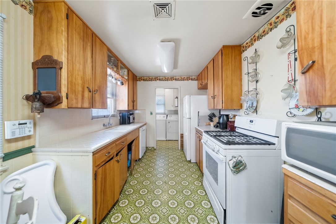 5433 Rochester Street Riverside, CA 92504 - Photo 4 of 29 Galley kitchen with wood cabinetry, tiled counters, gas range, and refrigerator.