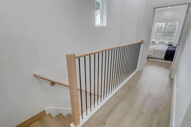 a view of a hallway with wooden floor and a bathroom