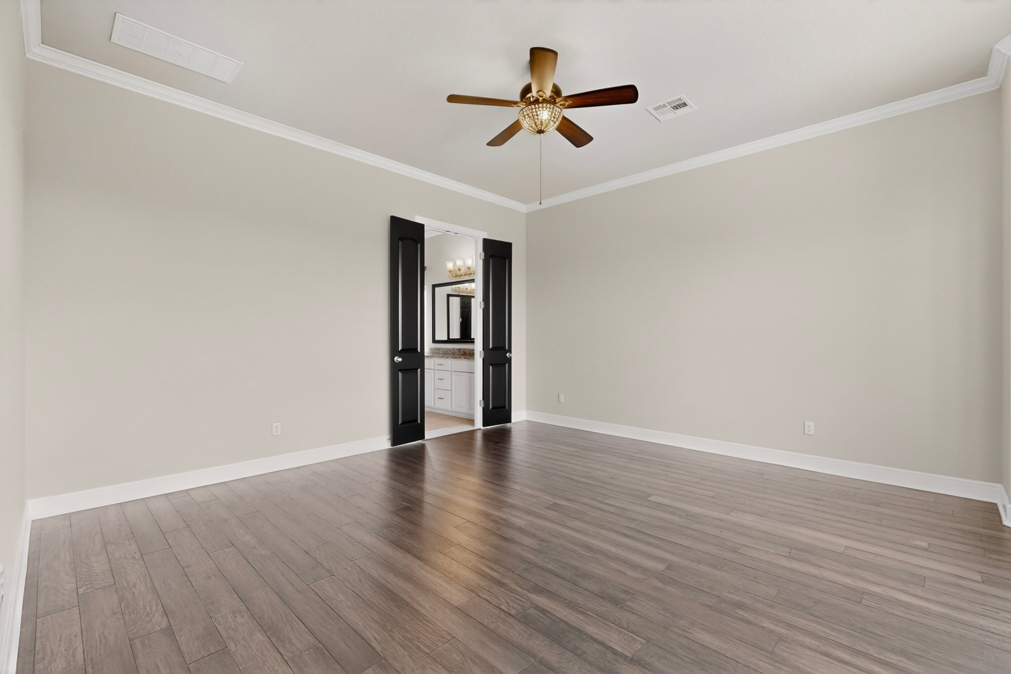 2617 Milan Meadows Drive Leander, TX 78641 - Photo 12 of 40 Well-lit primary bedroom featuring dark hardwood flooring and elegant crown molding.