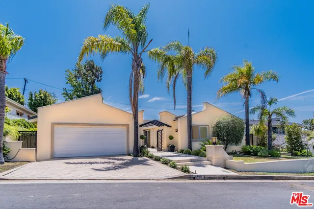 a view of a house with a small yard and palm trees