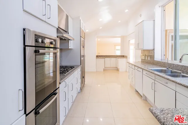 a kitchen with granite countertop white cabinets and stainless steel appliances