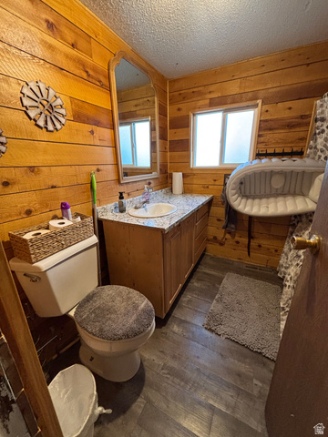 615 North 250 W Road Hinckley, UT 84635 - Photo 11 of 16 Bathroom featuring wood-finish wall paneling, a vanity with a white countertop and integrated sink, a large wall-mounted mirror, and wood-look flooring