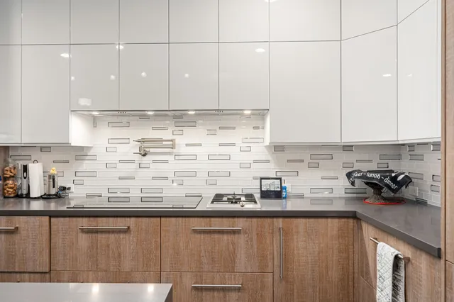 a kitchen with stainless steel appliances granite countertop a sink a stove and a white cabinets