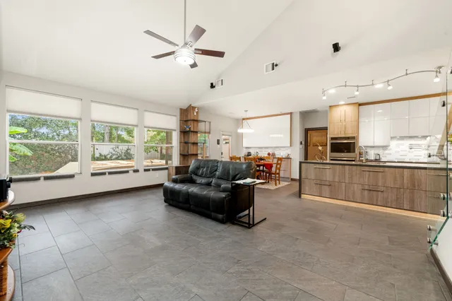 a living room with furniture and a large window with kitchen view